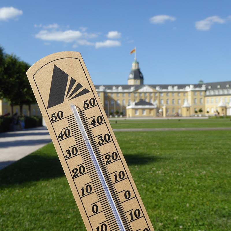 Im Vordergrund ein Thermometer und im Hintergrund das Karlsruher Schloss.