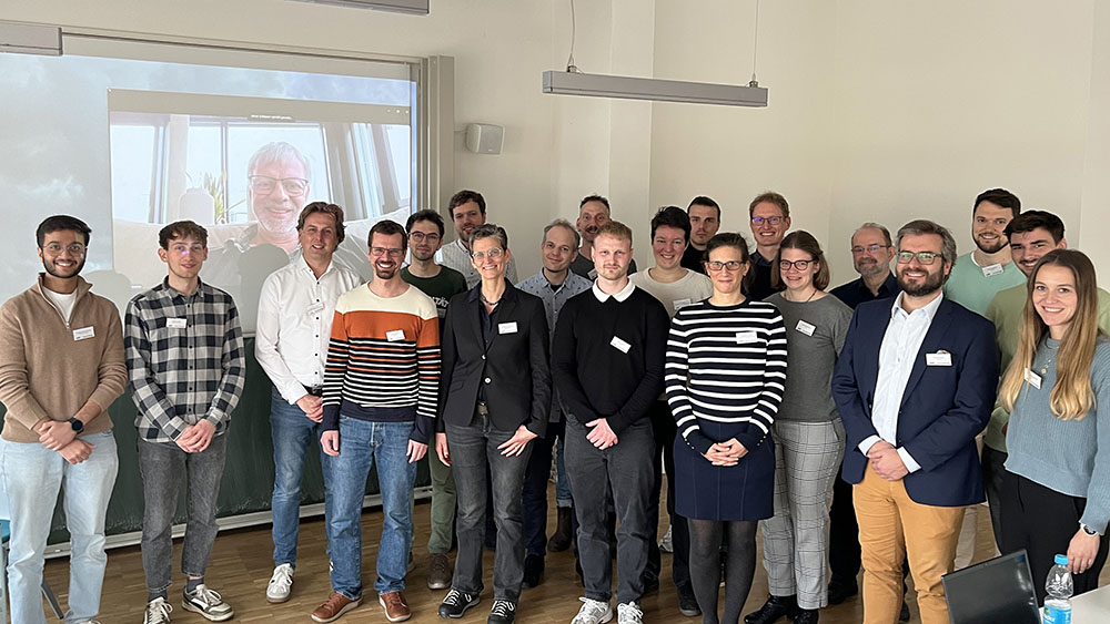 Gruppenfoto in einem hellen Seminarraum vor der Leinwand.